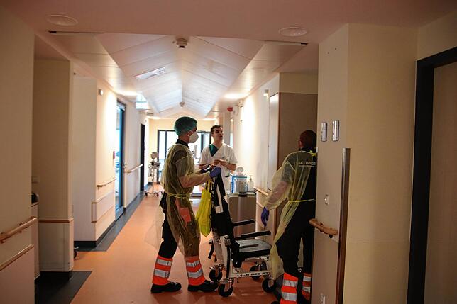 Ein Corona-positiver Mann wird vom Krankentransport abgeholt. Auch heute tragen die Pflegekräfte dann noch eine besondere Schutzkleidung.