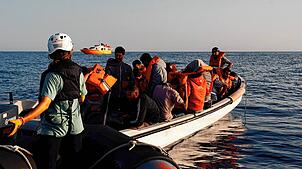 Während der ersten Rettungsmission im Mittelmeer rettet die Besatzung des Motorschiffes Sarah – im Hintergrund zu sehen – unter dem ...