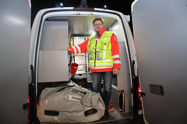 Alex Schroff im Materialbereich des Einsatzwagens. Unten liegt ein zusammen gefaltetes Zelt.
