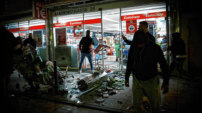 Menschen stehen am vergangenen Samstag vor einem geplünderten Geschäft in der Stuttgarter Marienstraße. Bei Auseinandersetzungen mit der ...