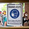 Schüler betreten hinter einem Plakat mit der Aufschrift &bdquo;Maskenpflicht&ldquo; am ersten Tag nach den Sommerferien den Eingang ...