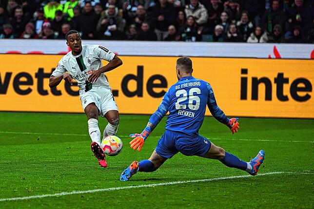 Gladbachs Alassane Plea (l) und Freiburgs Torwart Mark Flekken kämpfen um den Ball.