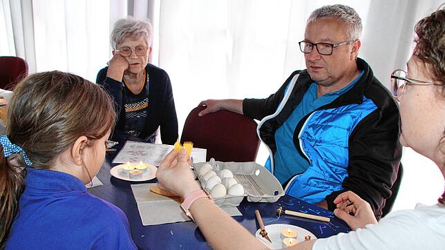 Charlotte Schanz, Sonja Bülow und Thomas Schanz lassen sich im Familienzentrum die Wachstechnik von Beáta Bléga zeigen. Foto: Heidi Rombach