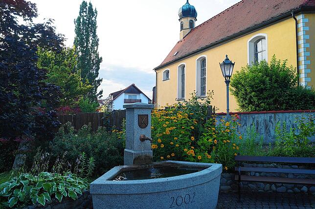 Üppig bepflanzt, bieten Dorfbrunnen und Kirche in Stetten als Ensemble ein schmuckes Bild.