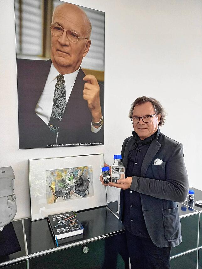 Unternehmer Frank Obrist hält klimaneutrales a-Methanol in den Händen. Hinter ihm ein Porträt von Felix Wankel, dessen Mitarbeiter ...