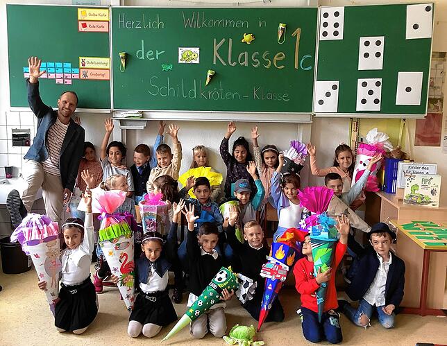 Die Klasse 1c der Grundschule Stockach hat mit Klassenlehrer Markus Bregenzer am ersten Schultag viel Spaß. Die Erstklässler winken fürs ...