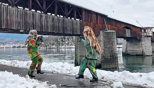 Zwei Maisenhardt-Joggele tanzen vor der Holzbrücke.