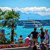 Touristen blicken am Überlinger Hafen auf die Fähre und den türkisblauen See.