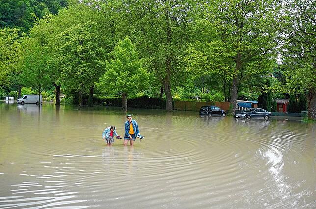 Seelandschaft in der Waldshuter Schmittenau: Diese beiden waten auf der Straße, die zum Schwimmbad führt, durch kniehohes, trübes ...