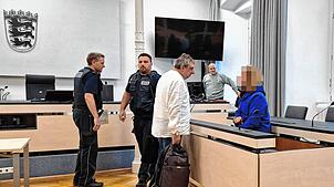 Der Angeklagte wird von den Wachtmeistern in den Gerichtssaal gebracht. Hier spricht er mit seinem Verteidiger Uwe Runge.