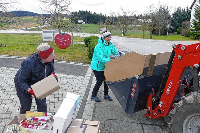 Die Landfrauen Britta Obergfell und Ingrid Schmid stapeln das auf den Gehwegen gelagerte Altpapier und die Kartons in die Ladeschaufel ...
