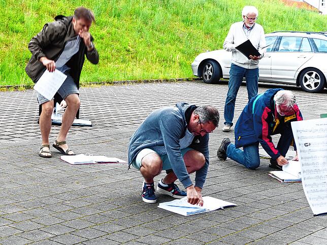 In Ermangelung eines Tisches oder Stuhls suchen die Mitglieder des Gospelchores am Boden nach den Notenblättern.
