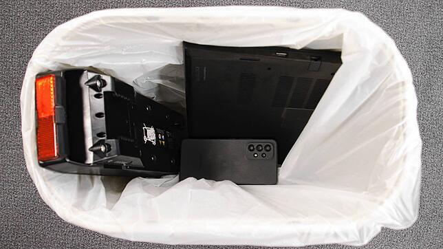 Ein Laptop, ein Handy und ein E-Bike-Akku liegen in eine Mülleimer: Ausgediente Akku-Geräte haben nichts im Hausmüll zu suchen, sondern ...