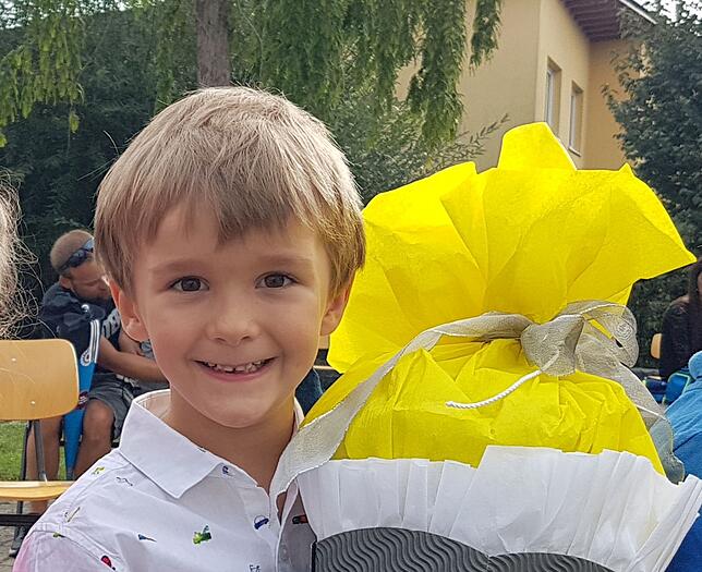 Vincent Freißmann mit Schultüte – draußen auf dem Schulhof, wie am Grün der Bäume gut zu erkennen ist.