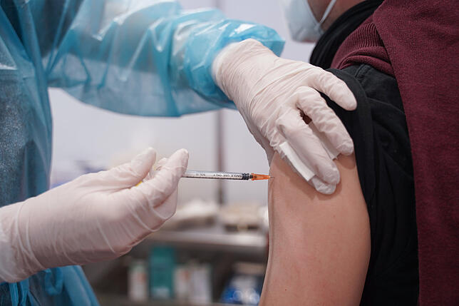 Ein junger Mann wird mit einer Booster-Dosis eines Corona-Impfstoffs gegen das Coronavirus geimpft.