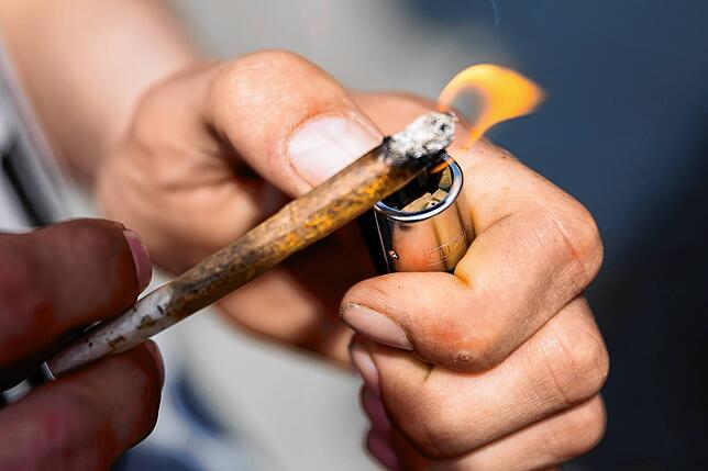 Ein Mann zündet sich einen Joint an (Symbolbild)