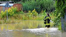 Eine Feuerwehrfrau watet durch Wassermassen in Markdorf.