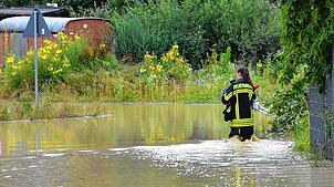 Eine Feuerwehrfrau watet durch Wassermassen in Markdorf.