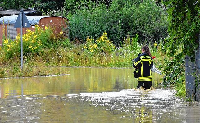Eine Feuerwehrfrau watet durch Wassermassen in Markdorf.