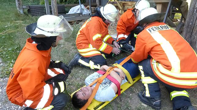 Die Feuerwehr Abteilung Nordhalden rettet bei ihrer Übung rasch den ohnmächtigen Jugendlichen aus dem in Brand geratenen Brennholzstapel.