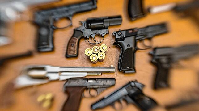 Pistolen, Revolver und Munition liegen auf einem Tisch in einer gesicherten Asservatenkammer (Symbolbild). In mehreren Verstecken ...