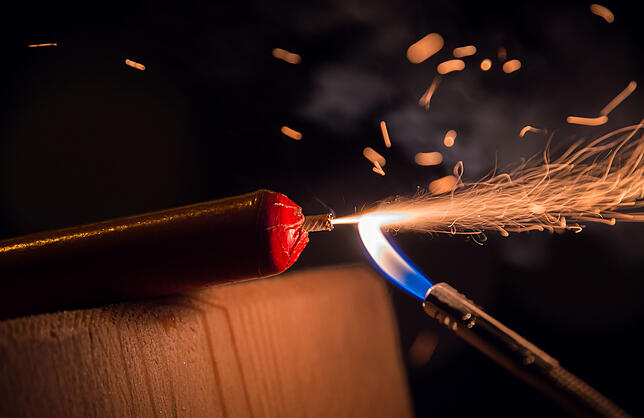 Ein Silvesterböller wird mit einem Feuerzeug gezündet.