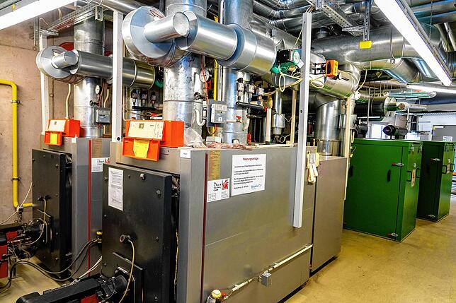 Im Vordergrund die alten Ölbrenner, in Grün dahinter die beiden gasbetriebenen Blockheizkraftwerke.