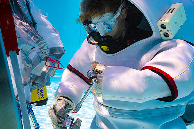 Eine Astronautin übt im Tauchanzug unter Wasser. Die Situation unter Wasser ist der Schwerelosigkeit im Weltall ziemlich ähnlich.