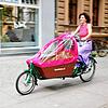 Eine Frau fährt mit einem Lasten-Fahrrad auf einem Radweg.