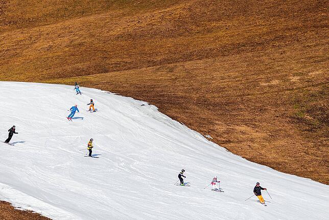 Skifahrer fahren in Filzmoos in Österreich über eine präparierte Skipiste.