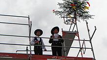 Die Zimmermannsleute Simon und Erwin Künstle (von links) sprechen hoch oben neben dem Richtbaum ihren feierlichen Spruch.