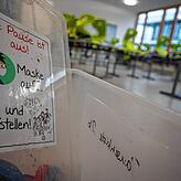 „Die Pause ist aus! Maske auf ... und aufstellen!“ steht in einer Gemeinschaftsschule in einer Grundschulklasse auf einem ...