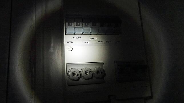 Sicherungskasten bei Stromausfall im Taschenlampenlicht.