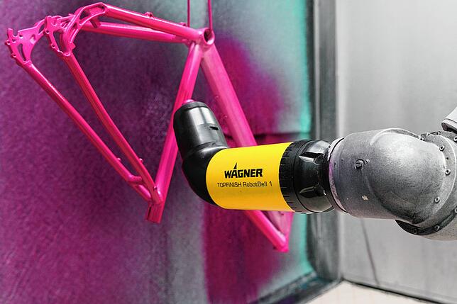Ein Sprühsystem von Wagner beschichtet einen Fahrraddrahmen. Warum so nicht auch Sonnencreme auf Haut auftragen, fragten sich die ...