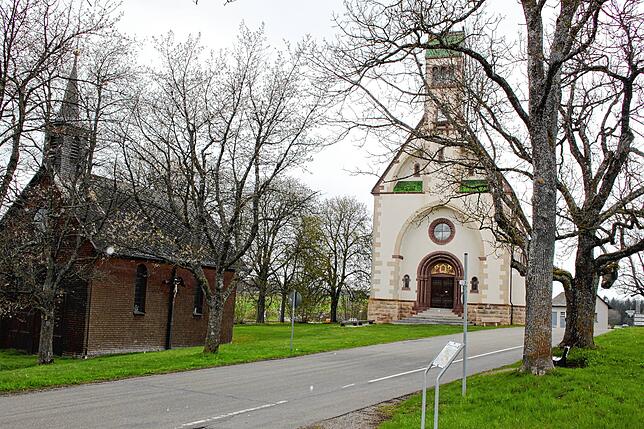 Links ist die alte hölzerne Kapelle zu sehen, die entrümpelt werden soll. Hinten steht die neue Wallfahrtskirche Witterschnee.