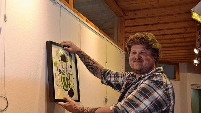 Tom Thiedmann beim Aufhängen seiner Bilder. Das Schwarzwaldmädel ist eines der wenigen größeren Bilder. Bild: Christiane Sahli