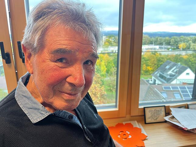Heinz Schmitt in seinem Zimmer. Im Hintergrund ist das Sportplatzareal zu erkennen, wo gerade ein neuer Kunstrasenplatz gebaut wird.