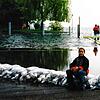 Susanna Katzschke sitzt am Überlinger Mantelhafen auf einer Barriere aus Sandsäcken. Der Bodensee im Hintergrund schwappt über die ...