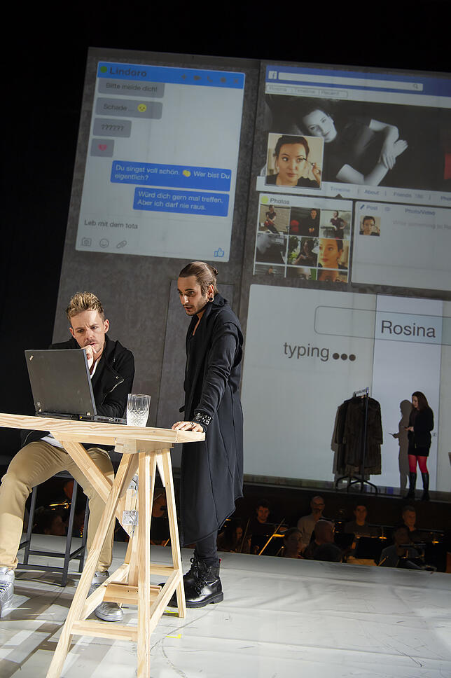 Almaviva (Alasdair Kent, links) und Figaro (Gurgen Baveyan) schauen sich Rosinas Facebook-Seite an.
