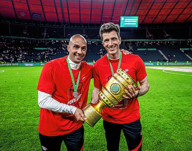 Die Leipziger Athletiktrainer Ruwen Faller (links) und Daniel Behlau präsentieren den DFB-Pokal 2022.