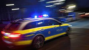 Ein Polizeifahrzeug fährt im Rahmen mit Blaulicht an einem Gebäude vorbei. (Symbolbild)