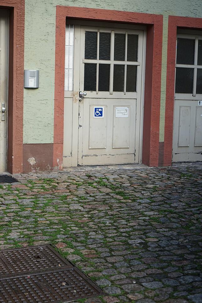 Über holprige Pflastersteine geht es zur öffentlichen Behinderten-Toilette an der Rückseite des Rathauses Tiengen.