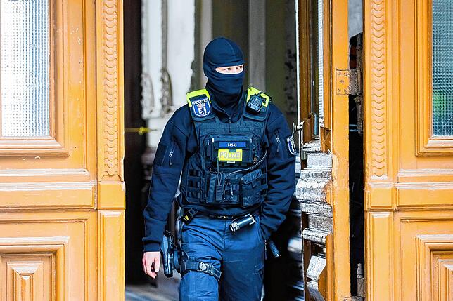 Berlin: Ein Polizist steht bei einer Hausdurchsuchung in Berlin-Kreuzberg in einem Hauseingang.