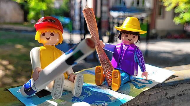 Die Stadtverwaltung möchte die Kita-Gebühren für Eltern, symbolisch dargestellt durch die Playmobil-Figuren vor dem katholischen ...