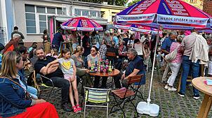 Die Besucher genießen die sommerliche Atmosphäre und das Zusammensein im Innenhof des Theaters am Turm.