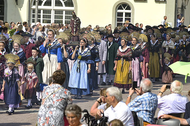 Der Prozessionszug am Hausherrensonntag erreicht den Marktplatz: Frauen der Trachtengruppe Alt-Radolfzell haben die Figur des Heiligen ...