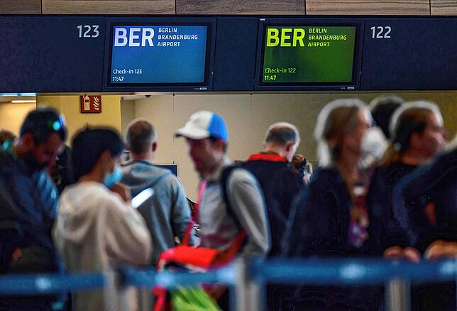Passagiere warten am Hauptstadtflughafen BER vor Check-in-Schaltern.