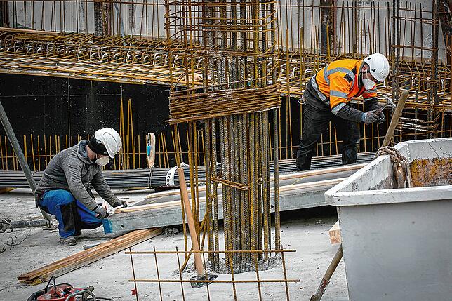 Bauarbeiter schützen sich auf der Baustelle mit Masken – Symbolbild aus dem März 2021.