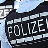 In Polizei-Westen gekleidete Polizisten stehen mit dem Rücken zur Kamera.