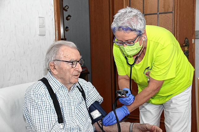 Die examinierte Altenpflegefachkraft Johanna Hipp (rechts) misst den Blutdruck bei Hermann Scheck (89 Jahre).
